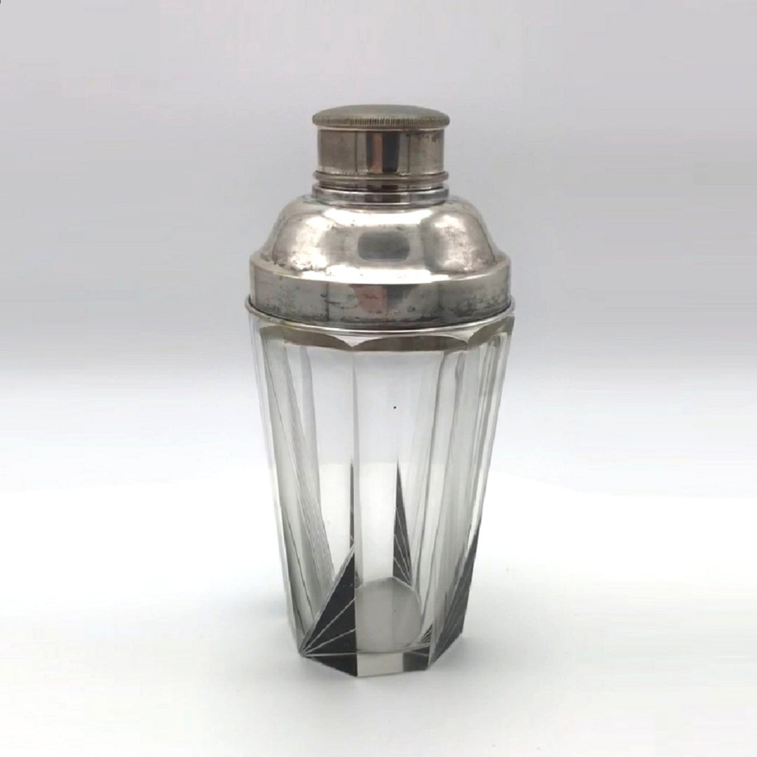 A vintage 1930s Karl Palda Art Deco Crystal Cocktail Shaker Czechoslovakia with a faceted clear crystal body, black enamel accents, and a polished silver metal lid, shown on a neutral light gray background.