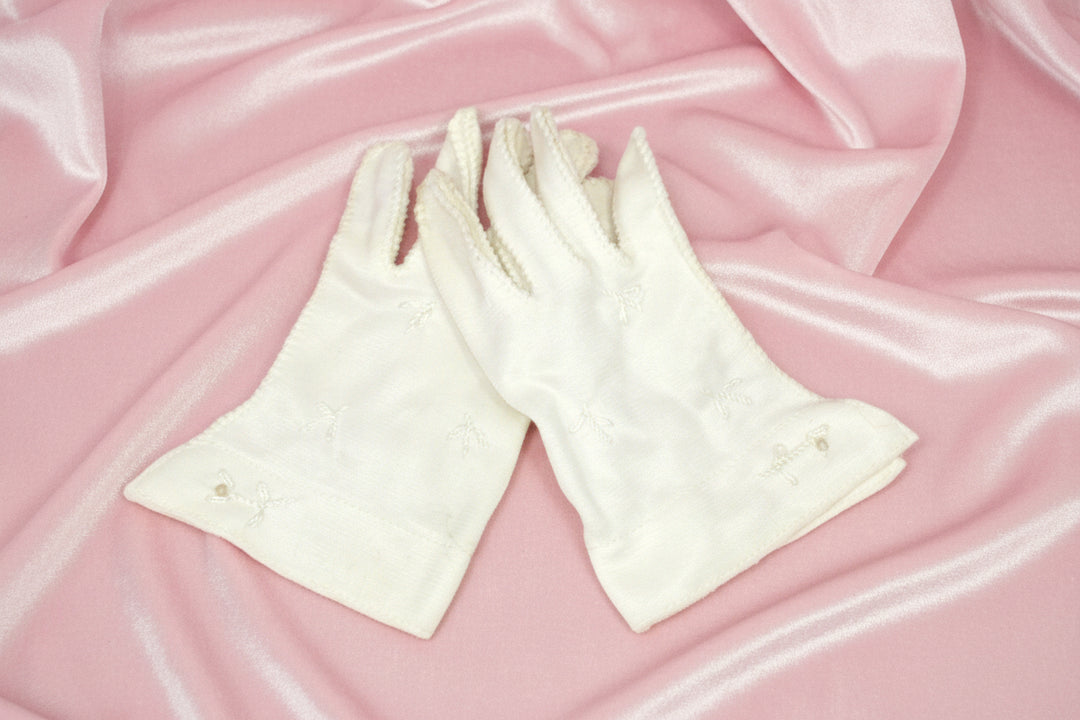 White vintage toddler girl's gloves on pink background.