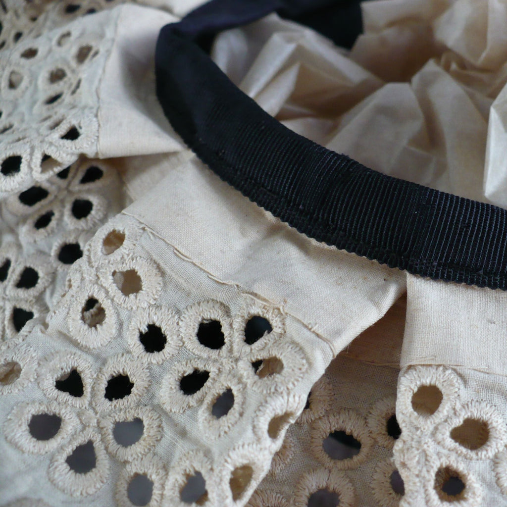 Close-up macro image of the fine tea-dyed lace and fabric construction on the Edwardian maid cap.