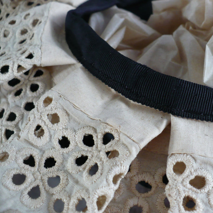 Close-up macro image of the fine tea-dyed lace and fabric construction on the Edwardian maid cap.