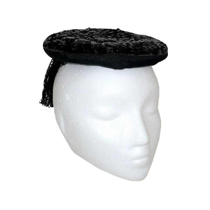 1930s black gelatin sequined percher hat worn on a white mannequin head, viewed from a three-quarter angle to the right, showing the mesh veil draping.