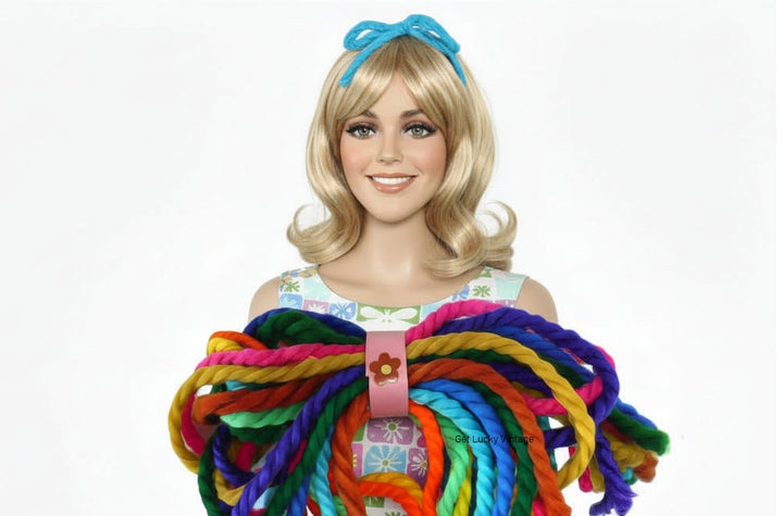 Mannequin  wearing vintage yarn hair tie headband, with a bundle of different colored headbands at base.