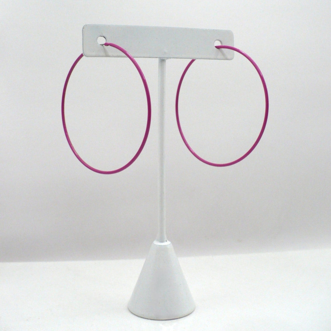 1980s pink pop art Memphis style 2-inch hoop earrings displayed on a white T-stand against a neutral white background.