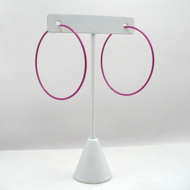 1980s pink pop art Memphis style 2-inch hoop earrings displayed on a white T-stand against a neutral white background.