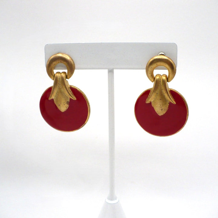 1980s vintage neo-baroque scarlet red and gold-tone door knocker statement earrings displayed on a white stand.