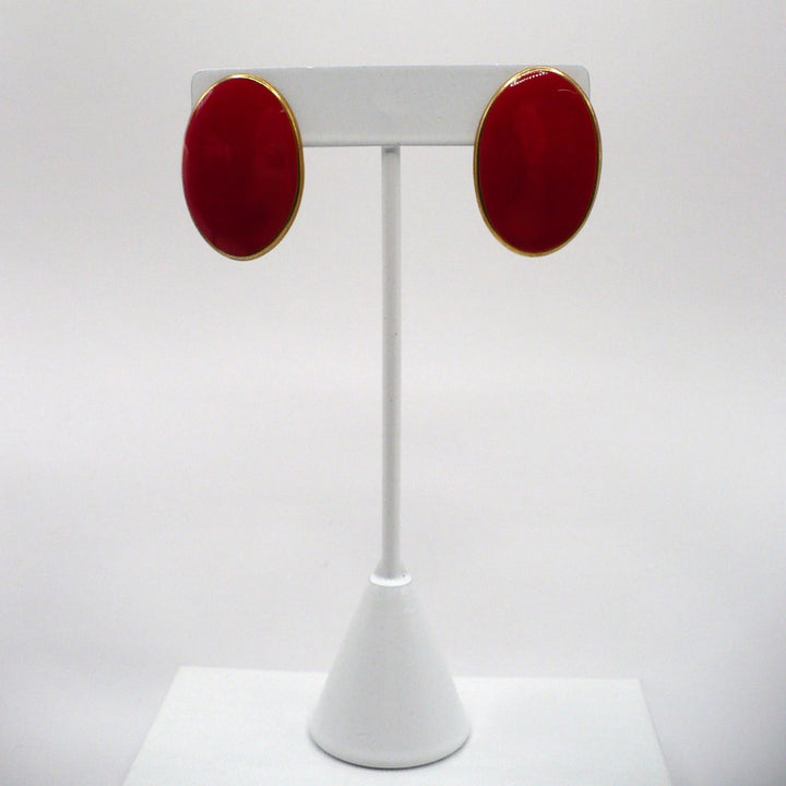 1980s vintage lipstick-red oval statement earrings with gold-tone outlines displayed on a tall white T-bar stand.
