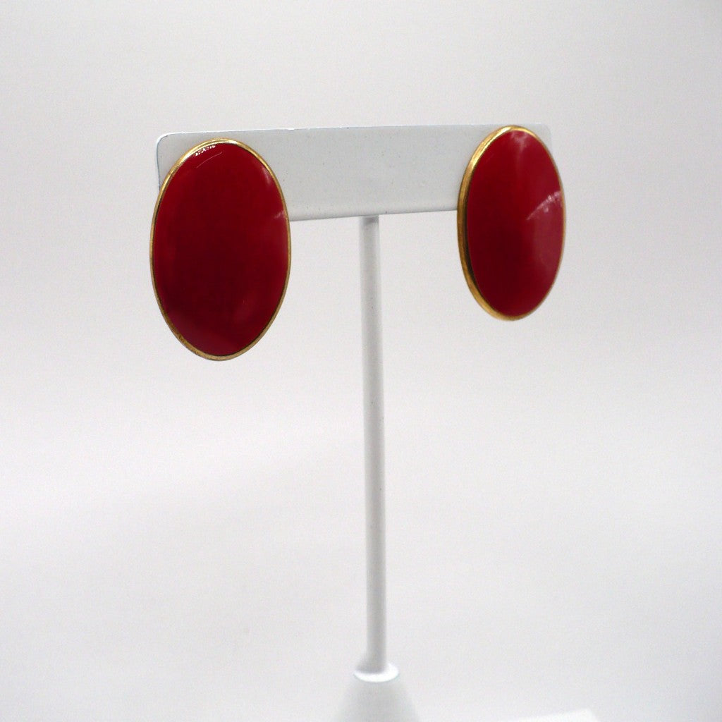 1980s vintage lipstick-red oval statement earrings with gold-tone outlines displayed on a white T-bar stand view at an angle.
