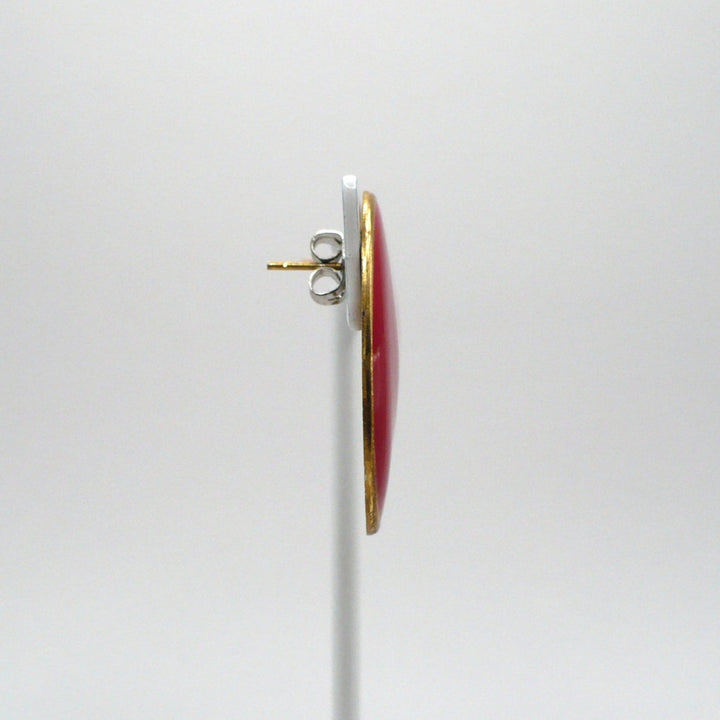 1980s vintage lipstick-red oval statement earrings with gold-tone outlines displayed on a white T-bar stand, side view.