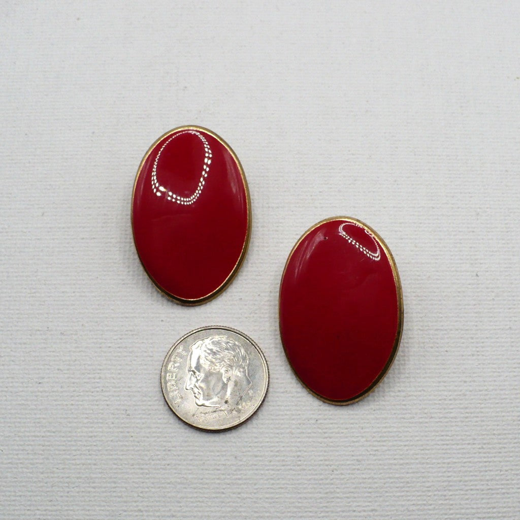 1980s vintage lipstick-red oval statement earrings with gold-tone outlines displayed on a white T-bar stand, on flat surface next to a dime for scale.