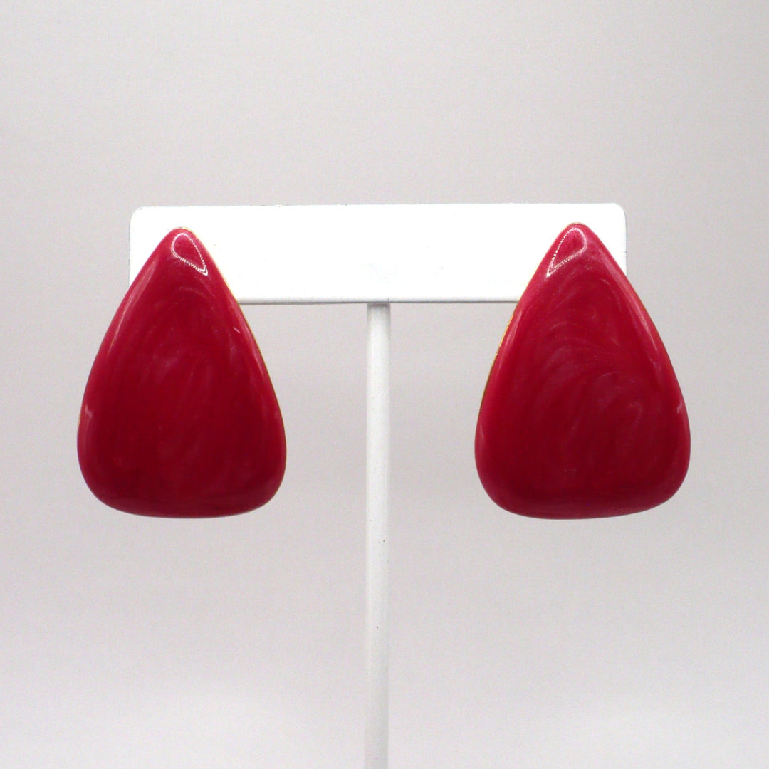 1980s vintage watermelon-pink marbled Lucite triangle statement earrings displayed on a white stand.