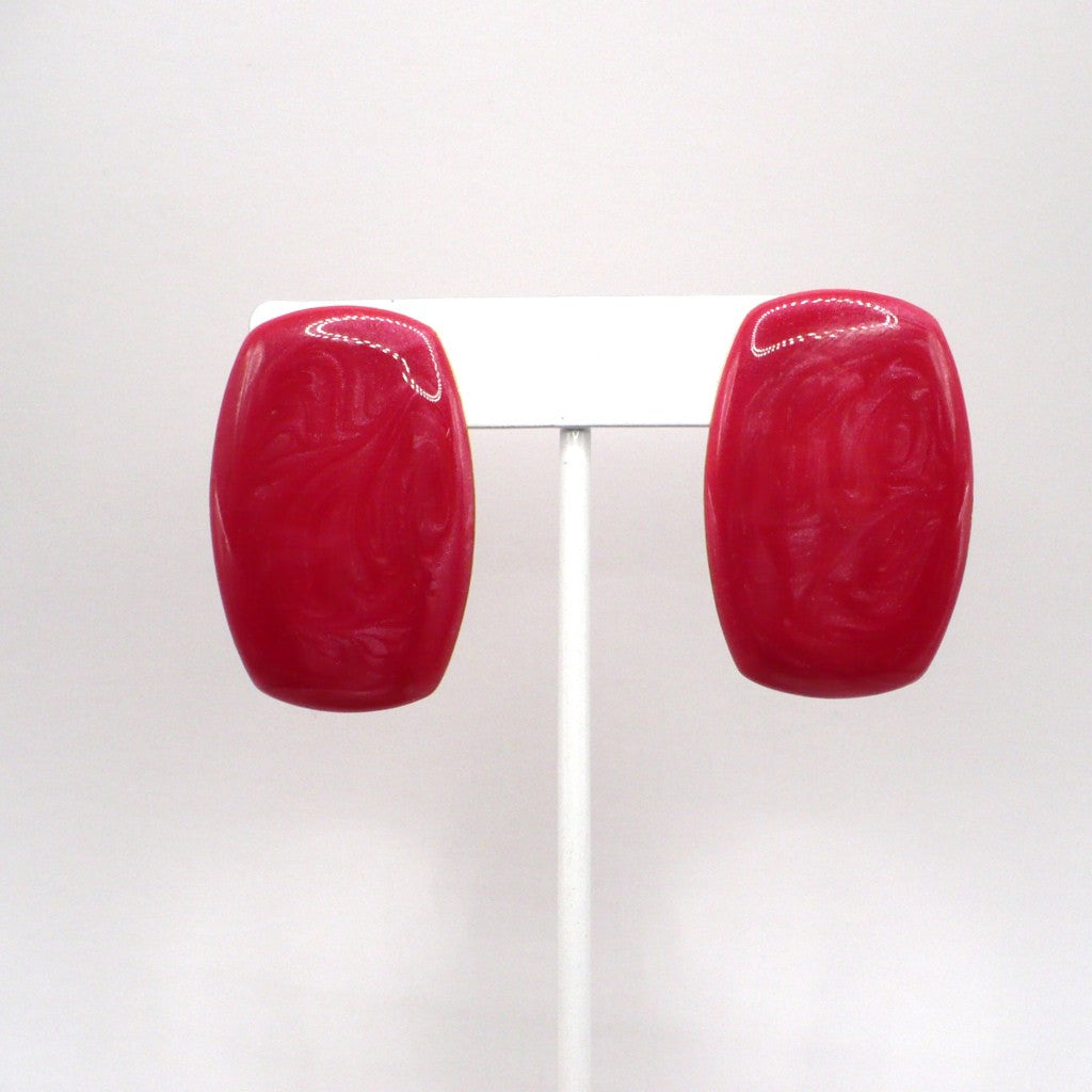 1980s vintage watermelon-pink marbled Lucite barrel statement earrings on a display stand.
