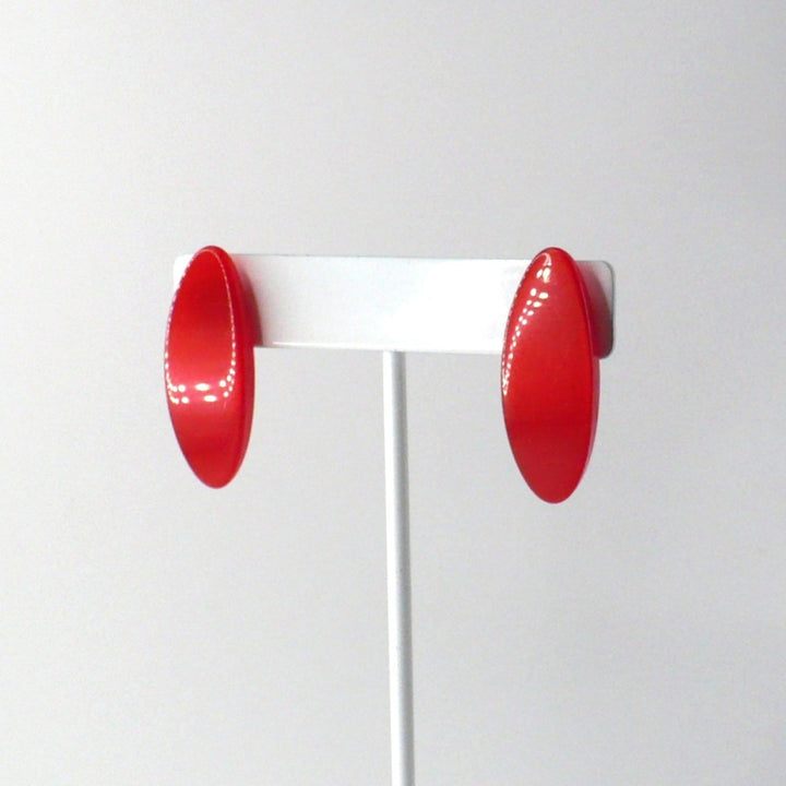 Translucent watermelon red geometric Lucite earrings with a high-shine finish on a display T-bar, left turning angle view.