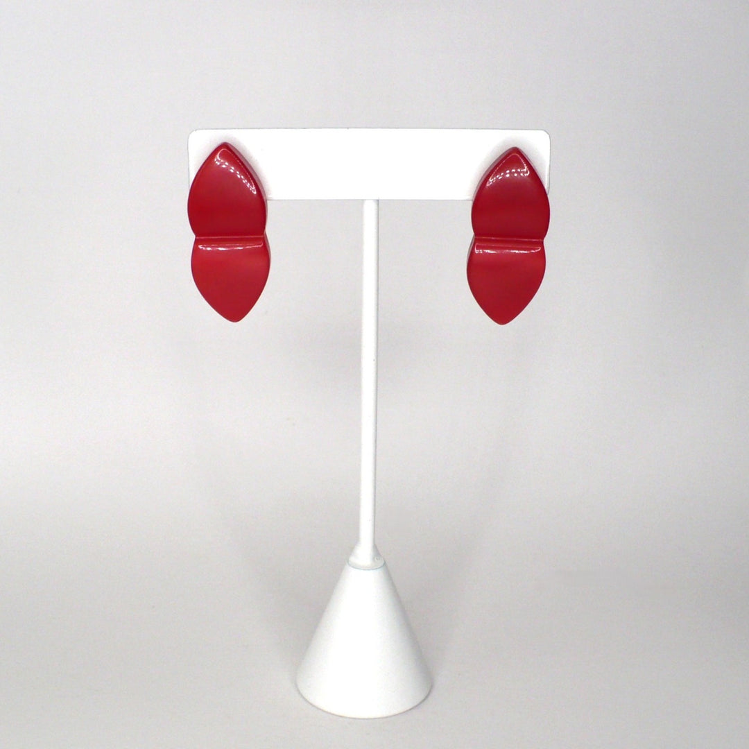 Pair of vintage 1980s New Wave watermelon red Lucite geometric statement earrings displayed on a white stand, facing forward.