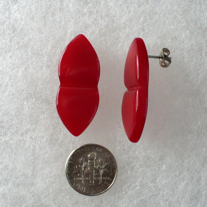 Pair of vintage red Lucite earrings laid flat with a coin for size comparison.