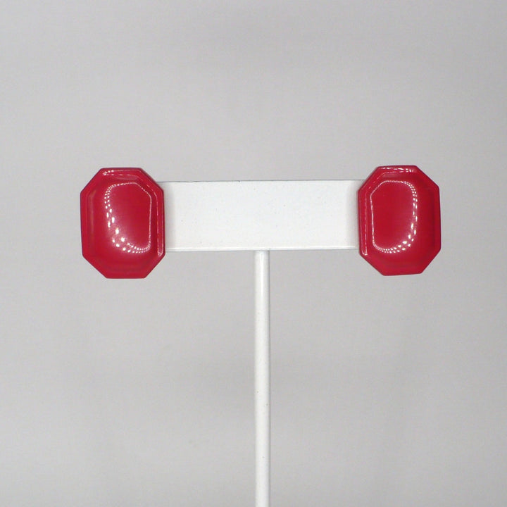 Pair of vintage 1980s New Wave watermelon pink enamel geometric button earrings displayed on a white stand.