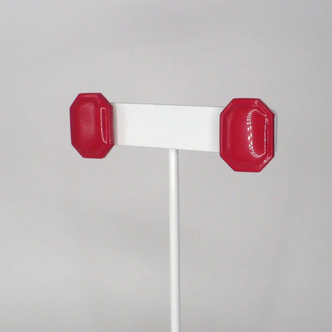 Pair of retro pink enamel statement earrings on a T-bar display shown at an angle.