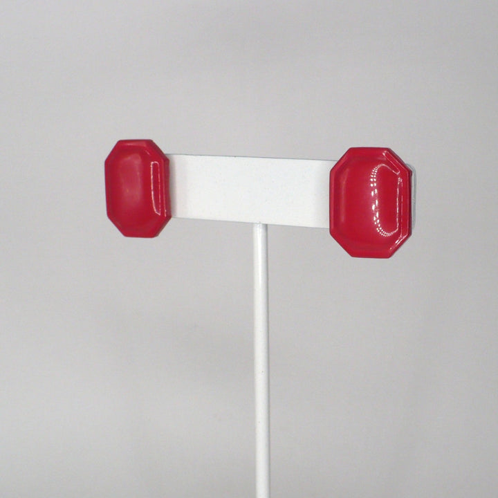 Pair of retro pink enamel statement earrings on a T-bar display shown at an angle.
