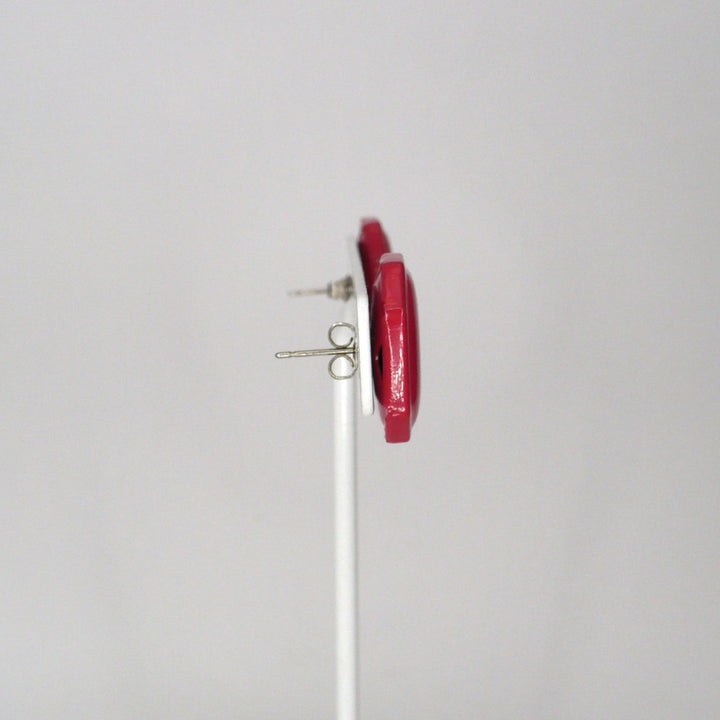 Pair of retro pink enamel statement earrings on a T-bar display shown side view.