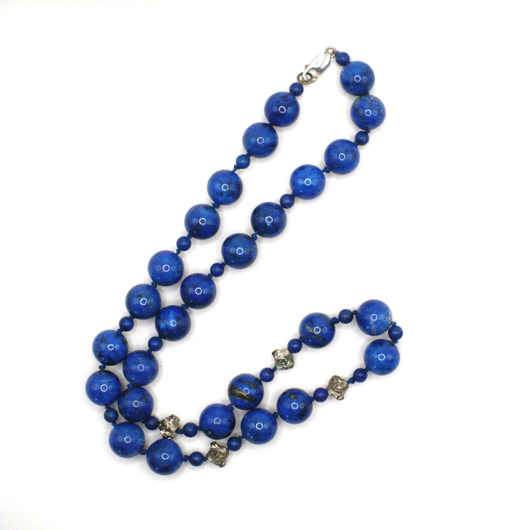 1970s vintage 27-inch opera-length lapis lazuli and sterling silver beaded necklace laid flat.