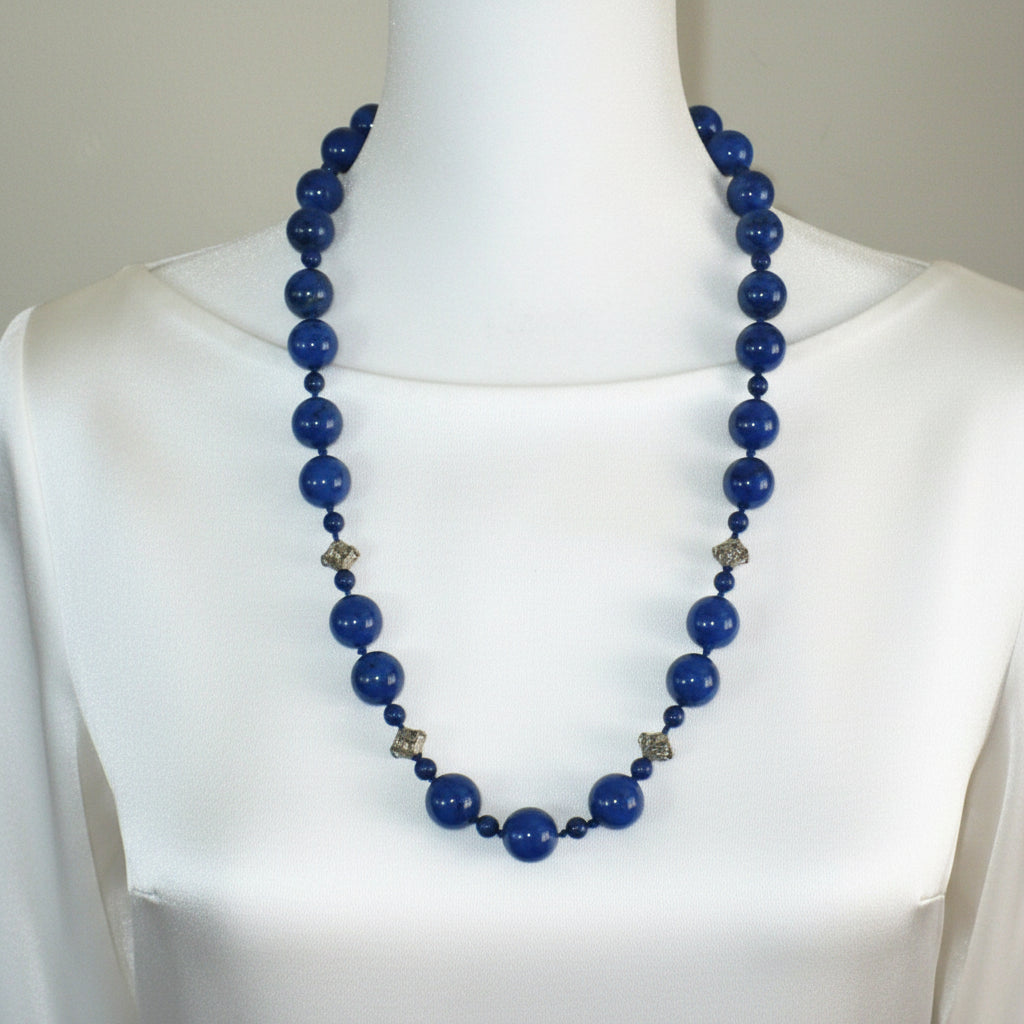 1970s vintage lapis lazuli beaded necklace displayed on a bust, showing the alternating bead sizes and sterling silver stations.