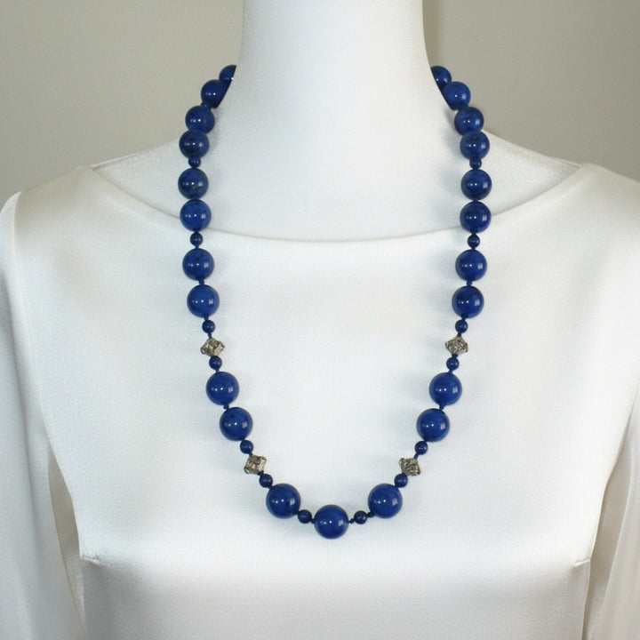 1970s vintage lapis lazuli beaded necklace displayed on a bust, showing the alternating bead sizes and sterling silver stations.