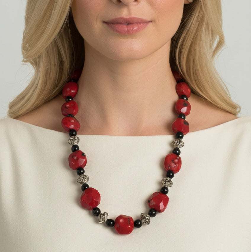 Woman wearing a 1970s vintage chunky red bamboo coral and black onyx opera-length necklace with sterling silver garlic twist spacers.