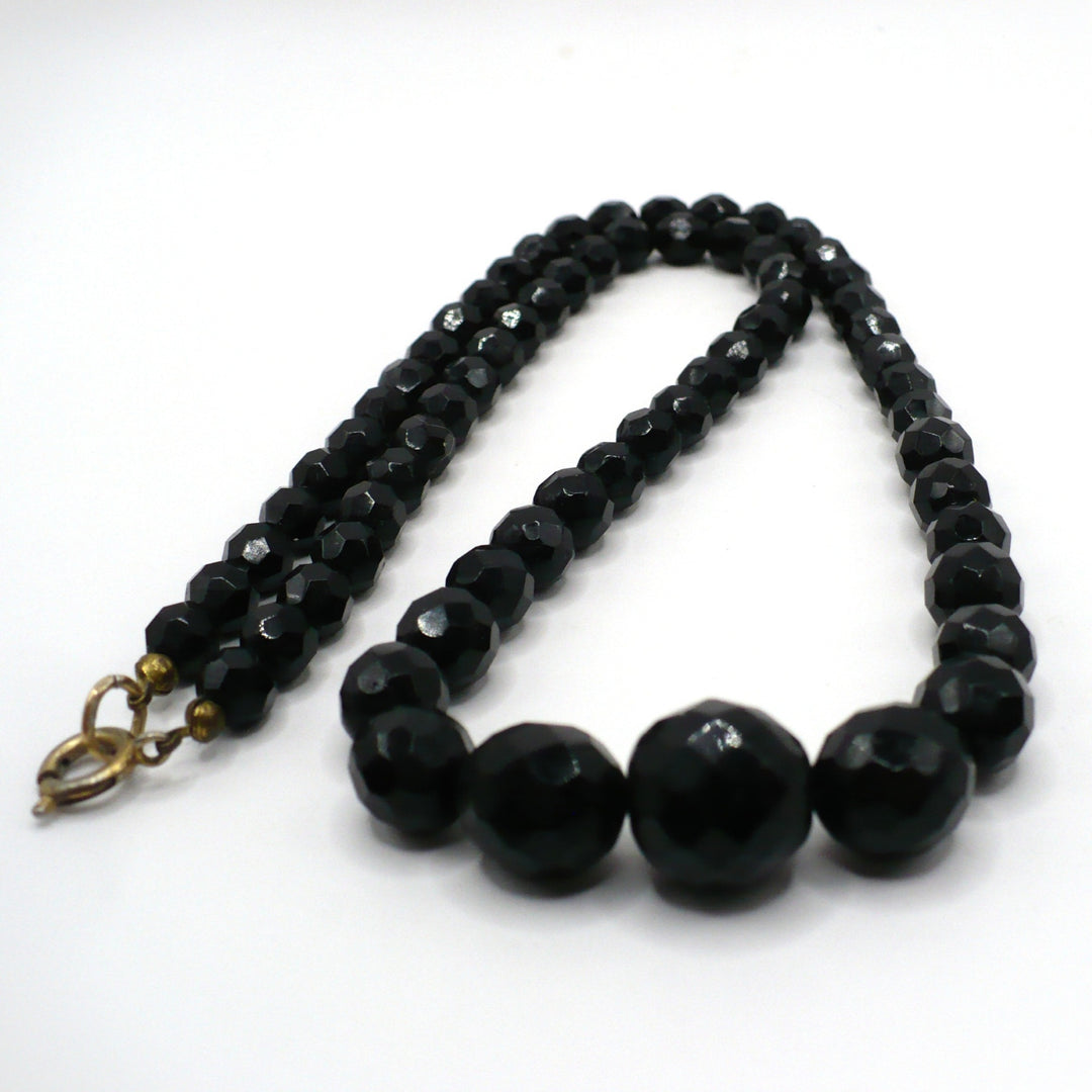 Close-up of the vintage 1950s black faceted glass beaded necklace showing graduated beads and clasp against a white background.