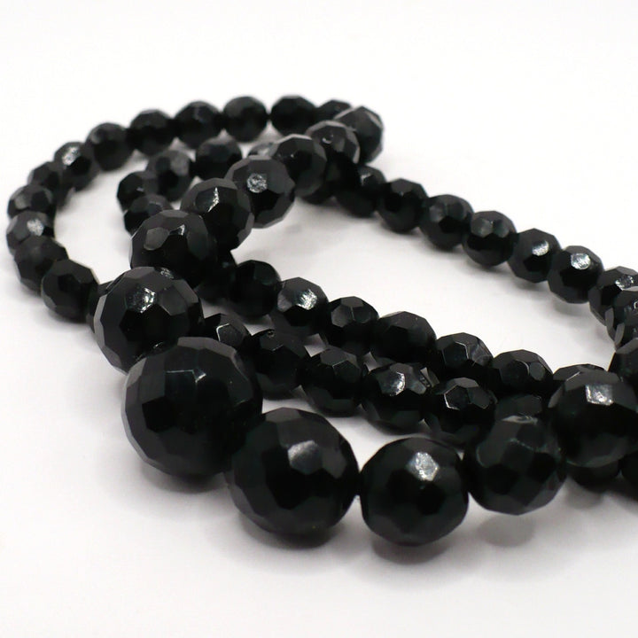 Macro close-up view of the graduated faceted black glass beads and texture on the 1950s vintage necklace.