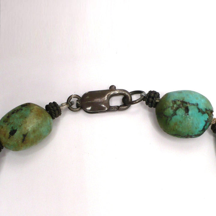 Close-up of the sterling silver lobster clasp and organic Hubei turquoise nugget beads on a 1970s vintage bohemian necklace.