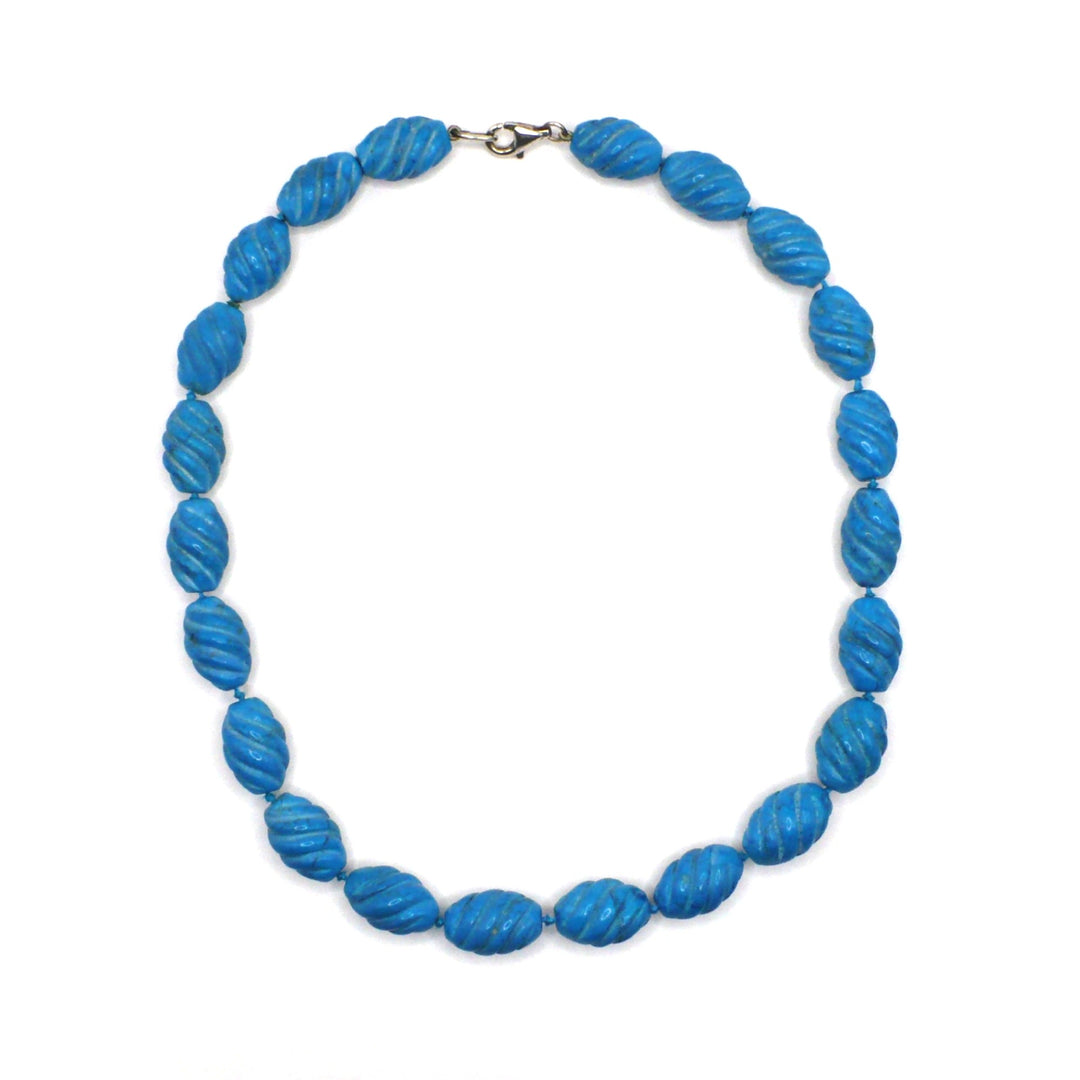 1970s vintage carved blue howlite beaded necklace with a sterling silver clasp displayed on a white background.
