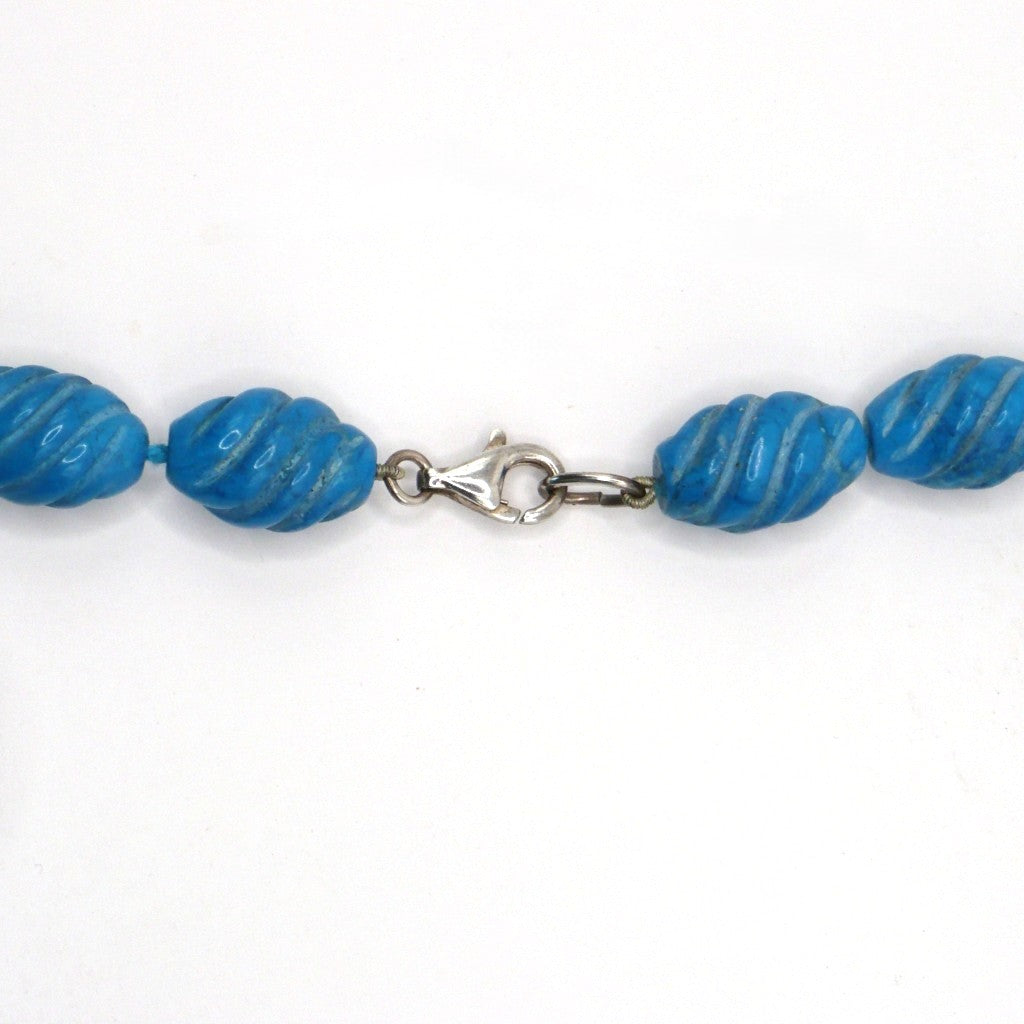 Close-up view of carved blue Howlite beads showing the detailed carving texture and sterling silver clasp.