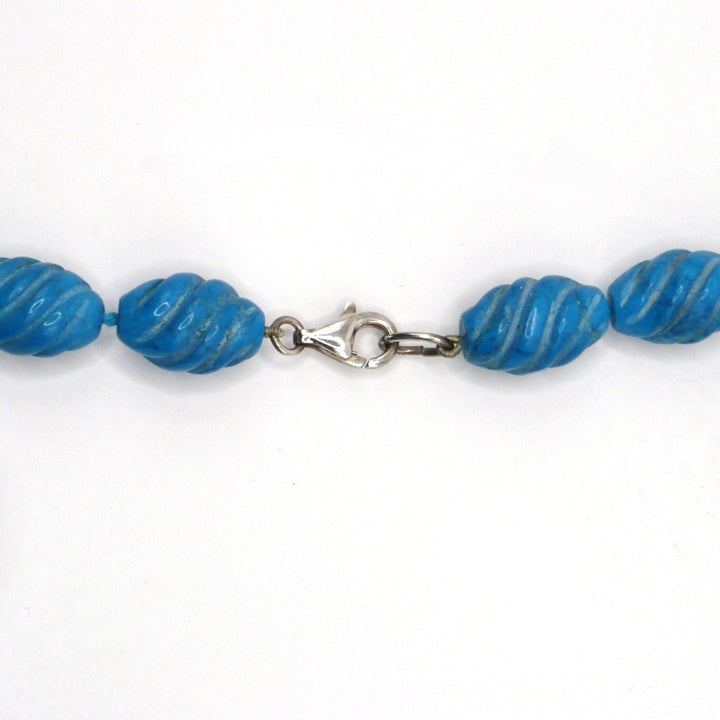 Close-up view of carved blue Howlite beads showing the detailed carving texture and sterling silver clasp.