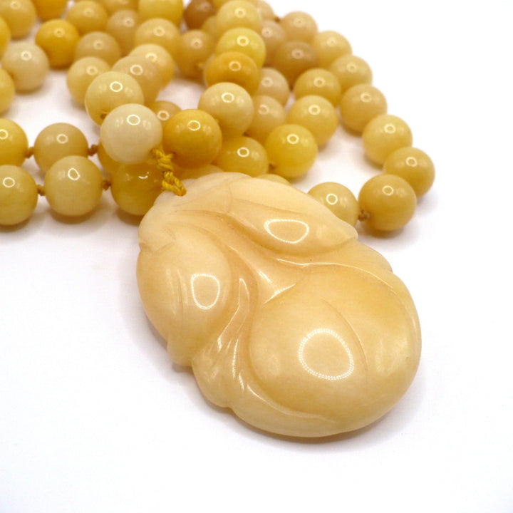Macro close-up photo of the carved yellow nephrite jade persimmon pendant and smooth round beads on the vintage 1970s necklace.