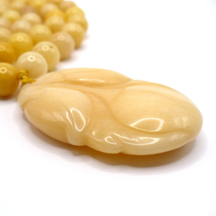 Macro shot of the carved yellow nephrite jade persimmon pendant, highlighting the smooth texture and warm tones of the vintage 1970s Chinese export necklace.