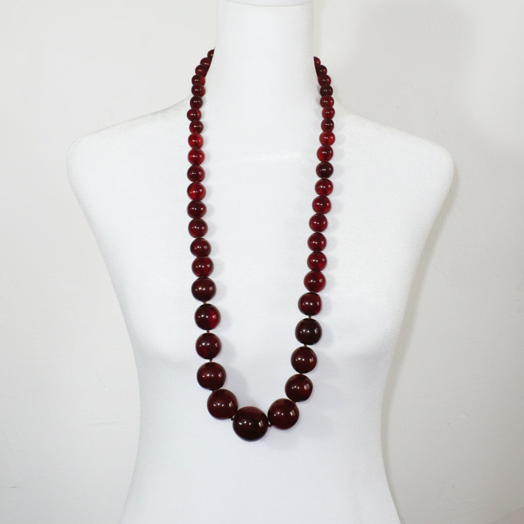 Vintage opera-length 1920s cherry amber graduated bead necklace styled on a mannequin.