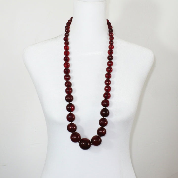 Vintage opera-length 1920s cherry amber graduated bead necklace styled on a mannequin.