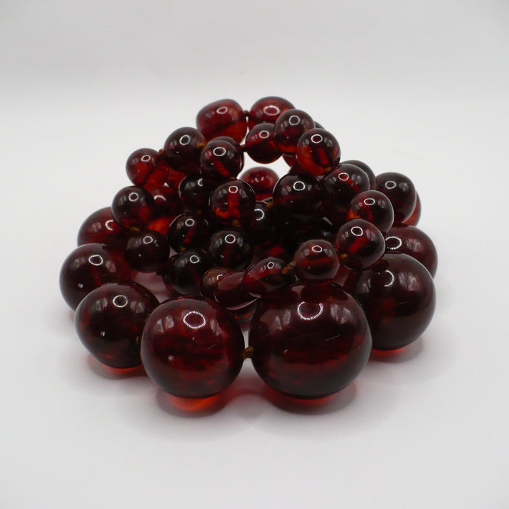 Macro close-up view of large, graduated antique cherry amber beads showing natural organic hue.
