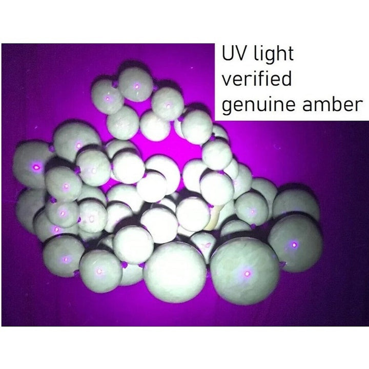 UV light verification test of antique cherry amber necklace showing natural authentication fluorescence.