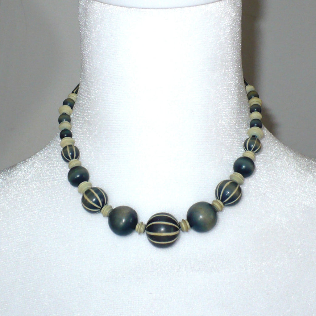 1970s vintage beaded choker necklace featuring blue-grey and cream striped wood beads and carved camel bone spacers, displayed on a white mannequin form.