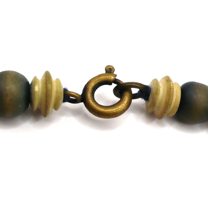 Close-up of a brass spring-ring clasp and carved camel bone spacers on a 1970s vintage beaded necklace.