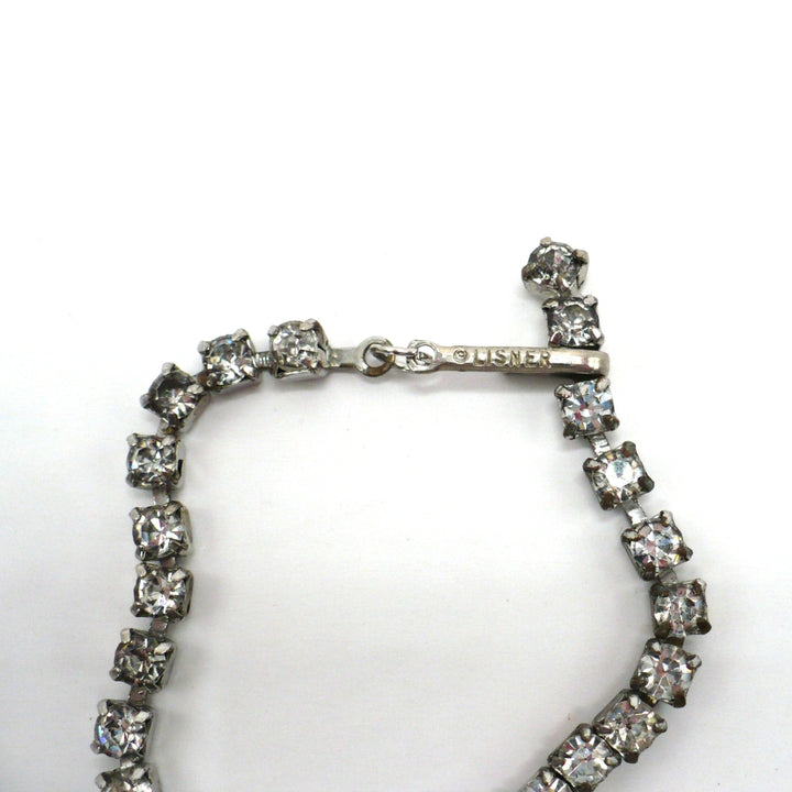 Signed vintage Lisner rhinestone festoon necklace close-up view showing the hook clasp and maker's hallmark stamp.