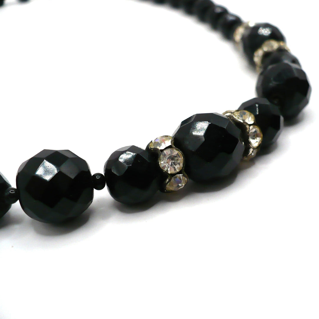 Macro close-up of graduated black faceted glass beads and sparkling rhinestone rondelles on the 1950s vintage necklace.