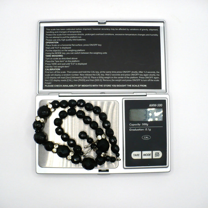 Vintage 1950s graduated black faceted glass beaded necklace with rhinestone rondelles weighed on a digital scale.
