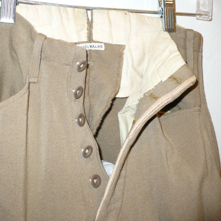A close-up of A pair of children's vintage equestrian breeches in a muted taupe-brown color, featuring vegetable ivory button fly close-up.