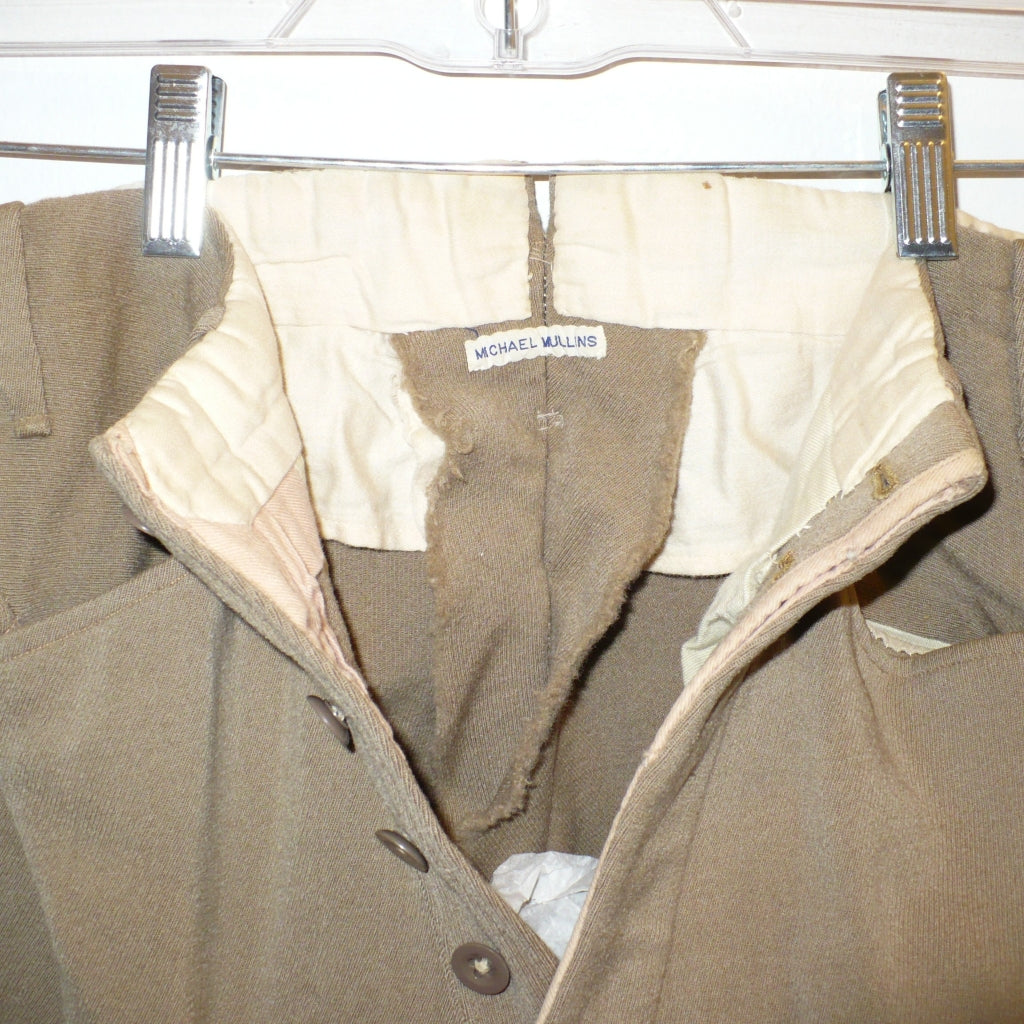 A close-up of A pair of children's vintage equestrian breeches in a muted taupe-brown color, featuring vegetable ivory button fly close-up. of label.