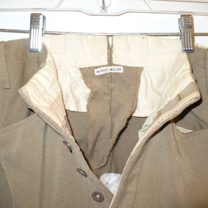 A close-up of A pair of children's vintage equestrian breeches in a muted taupe-brown color, featuring vegetable ivory button fly close-up. of label.