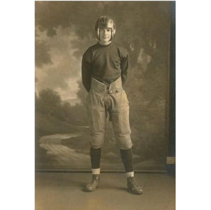 Vintage photograph of a football player in uniform against a scenic backdrop