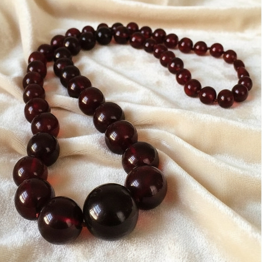 Edwardian to 1920s Vintage Cherry Amber Beaded Necklace shown on velvet fabric.