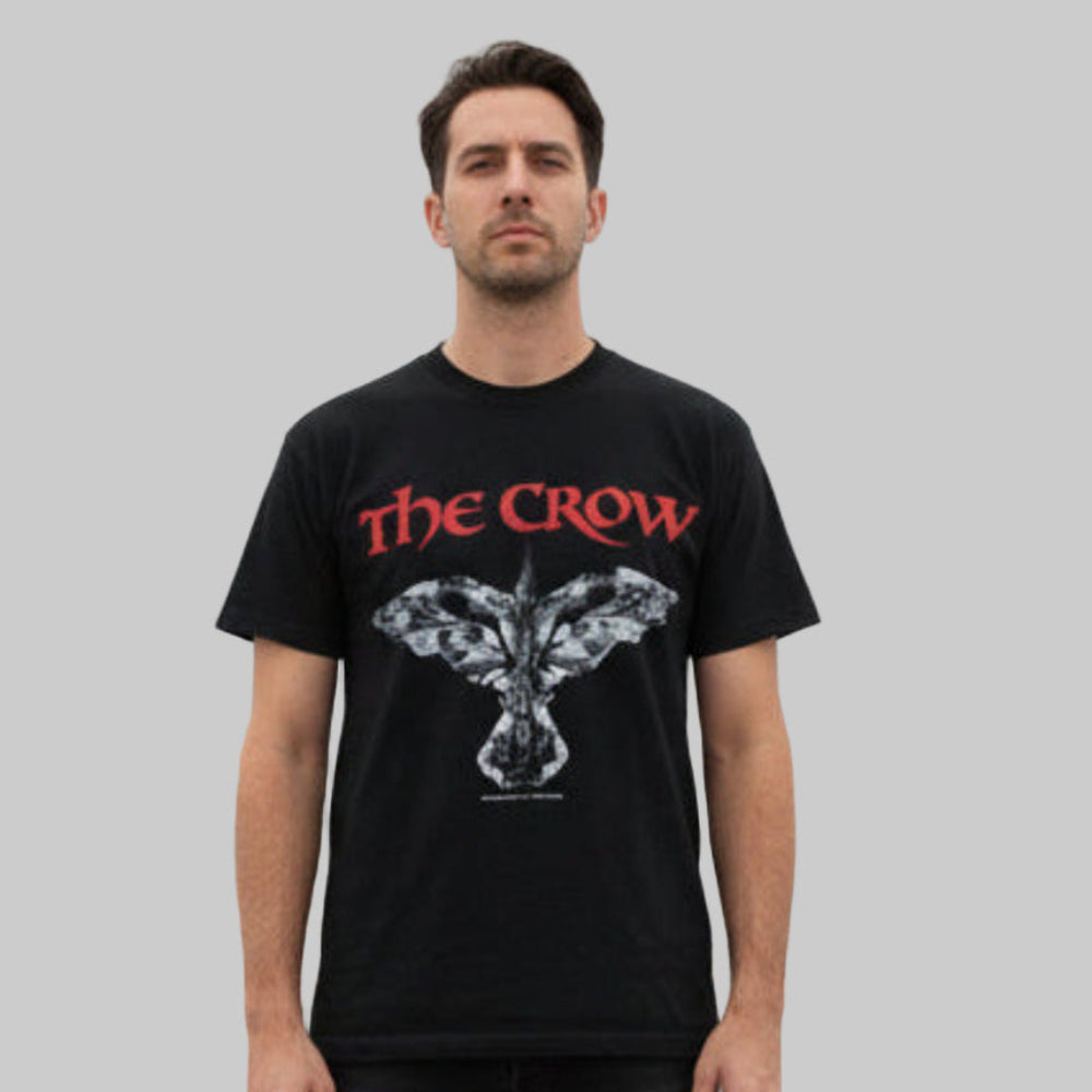 Man wearing a black vintage t-shirt with 'The Crow' logo on a gray background.