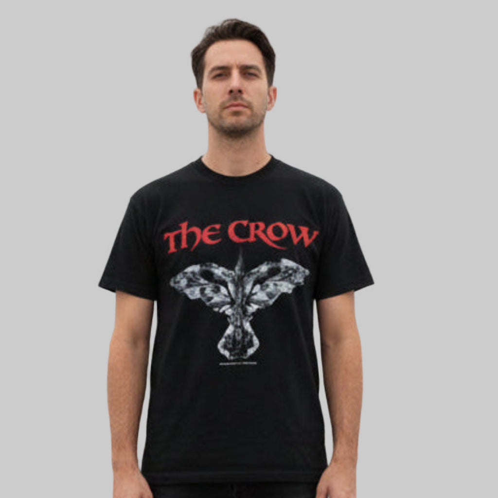 Man wearing a black vintage t-shirt with 'The Crow' logo on a gray background.